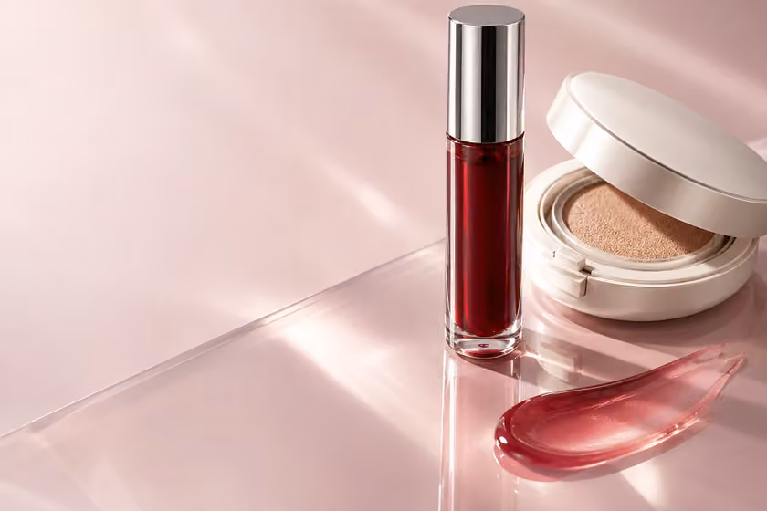 Cherry lip colour and an ivory compact arranged on a blush studio surface